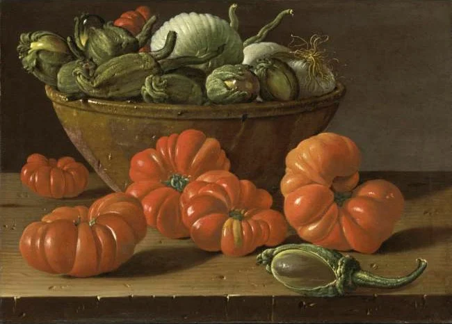Ribbed heirloom tomatoes on a wooden ledge in front of an earthenware bowl of aubergines and onions.